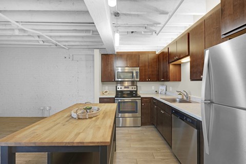 A kitchen with a wooden table and stainless steel appliances.