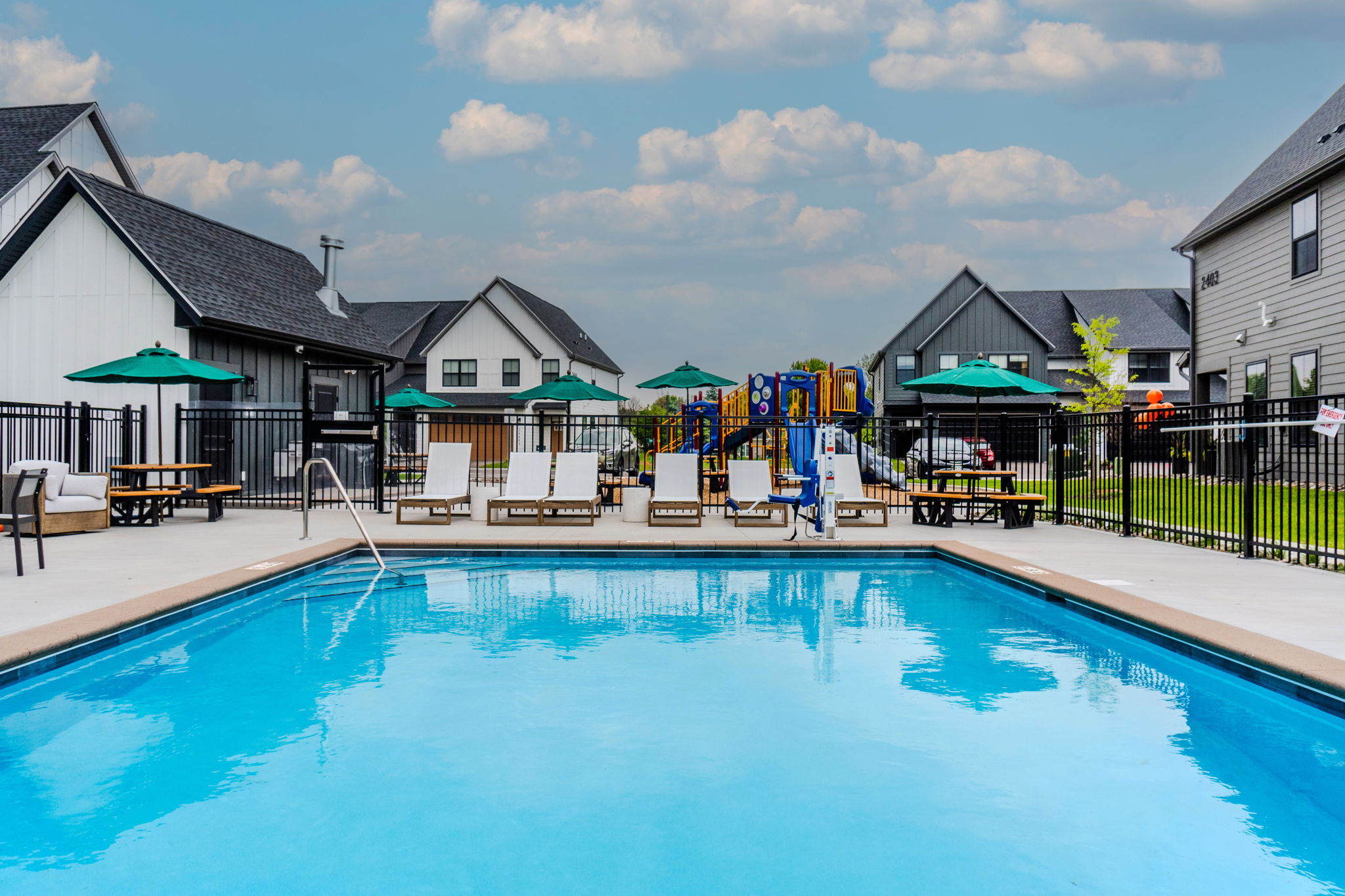 A swimming pool with a blue tinted water and a black fence around it.