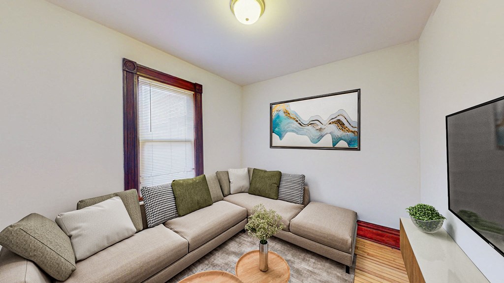 A living room with a grey couch and a painting on the wall.