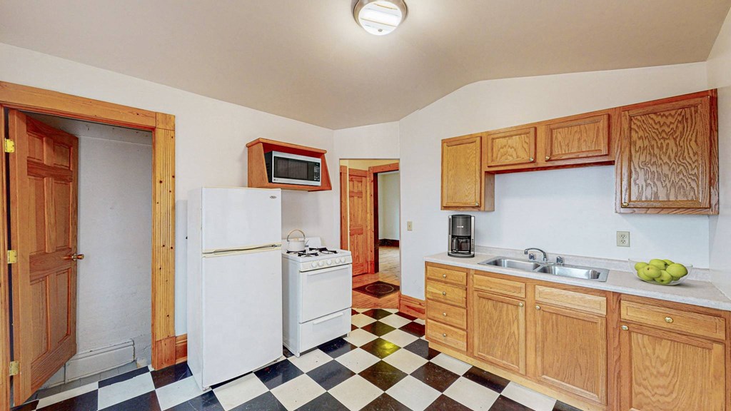 A kitchen with white appliances and wooden cabinets.