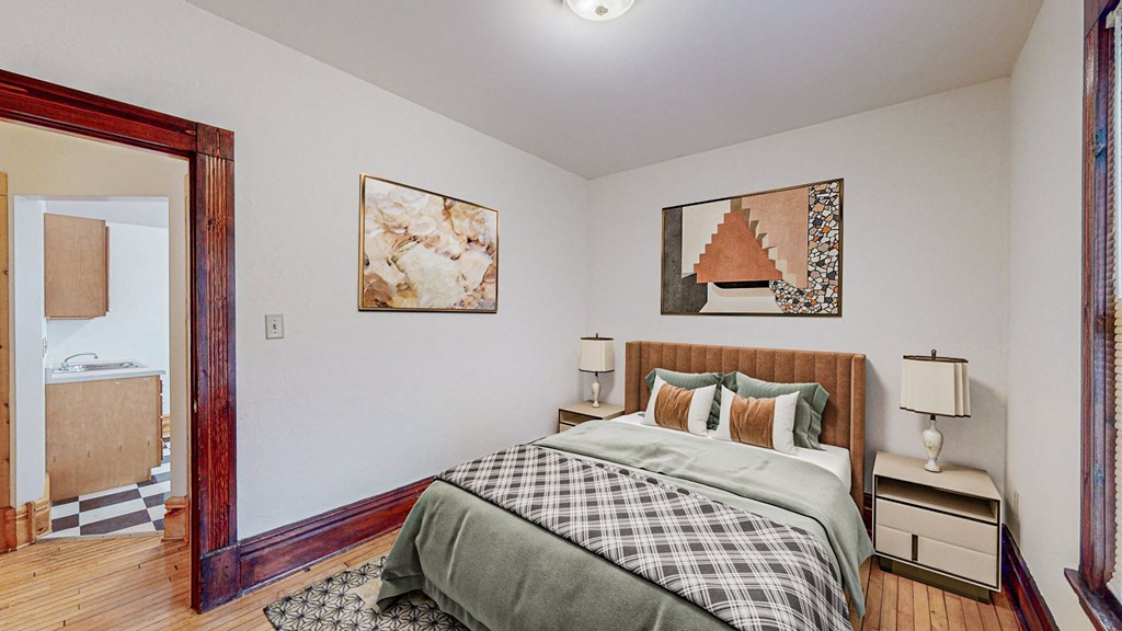 A bedroom with a bed, nightstands, and two pictures on the wall.