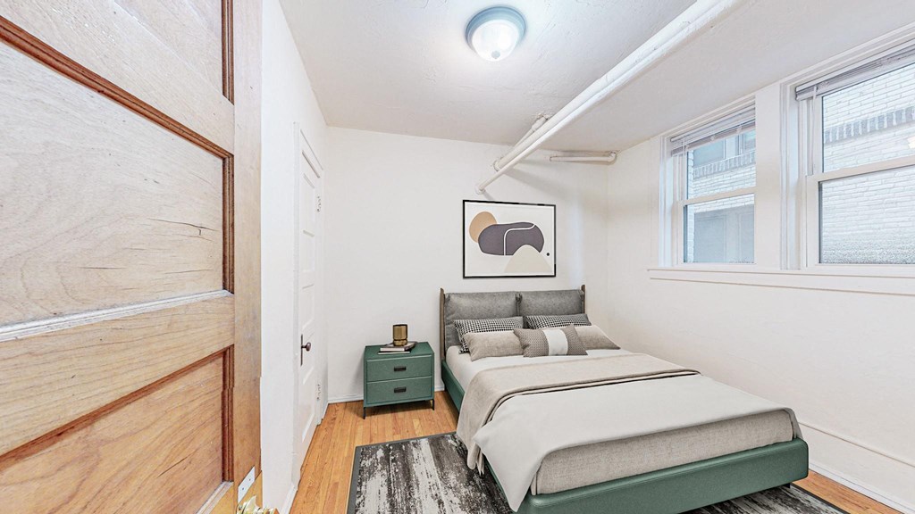 A bedroom with a bed, nightstand, and a painting on the wall.