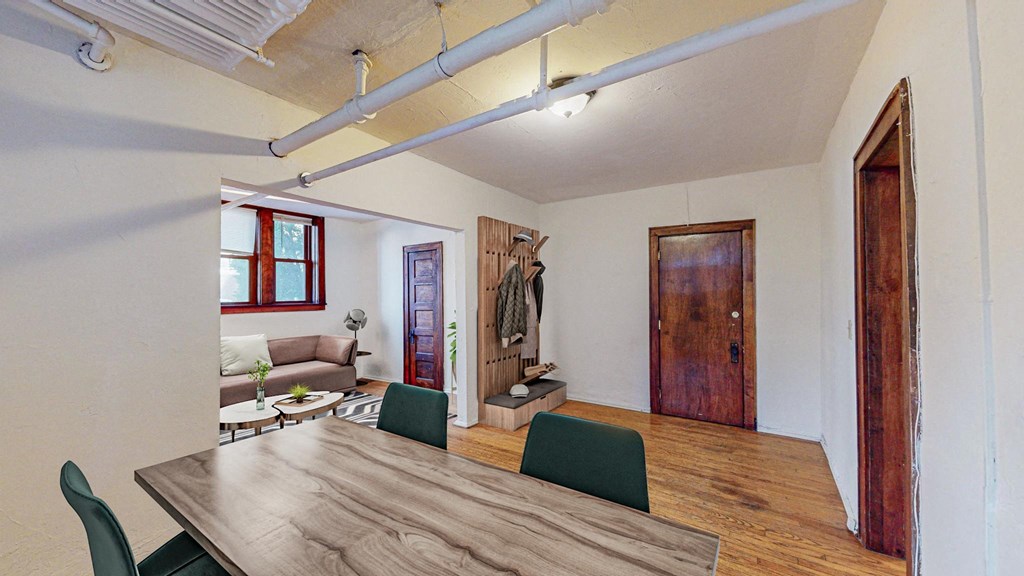 A room with a long wooden table and green chairs.