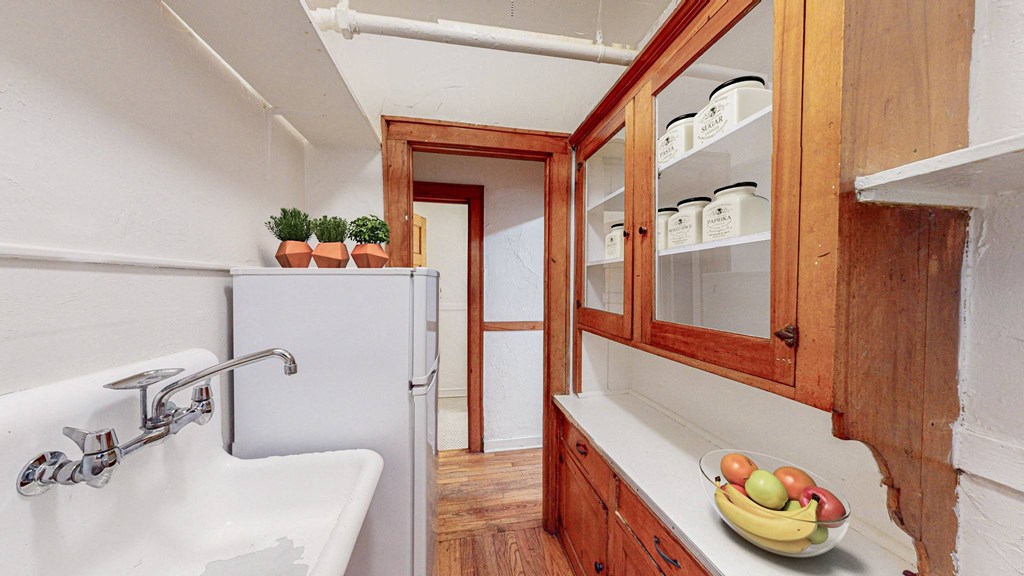 A kitchen with a white sink and wooden cabinets.