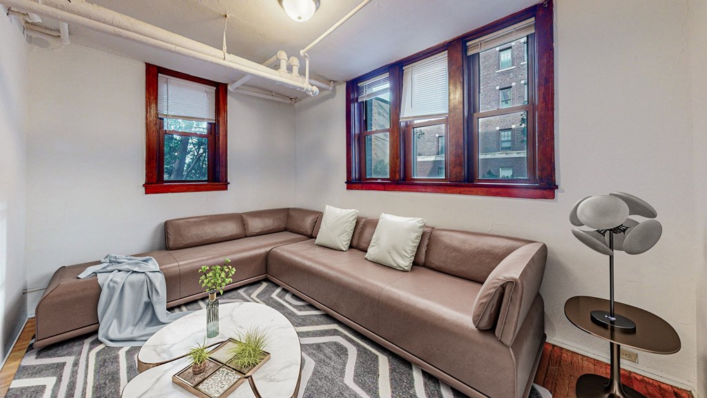 A living room with a brown couch, a small table with a vase and a plant, and a floor lamp.