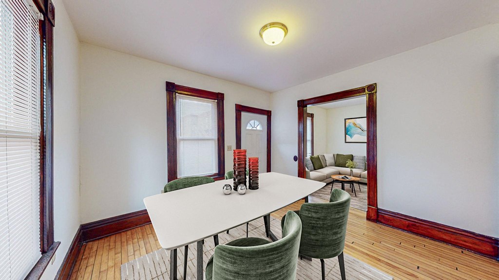 A dining room with a white table and green chairs.