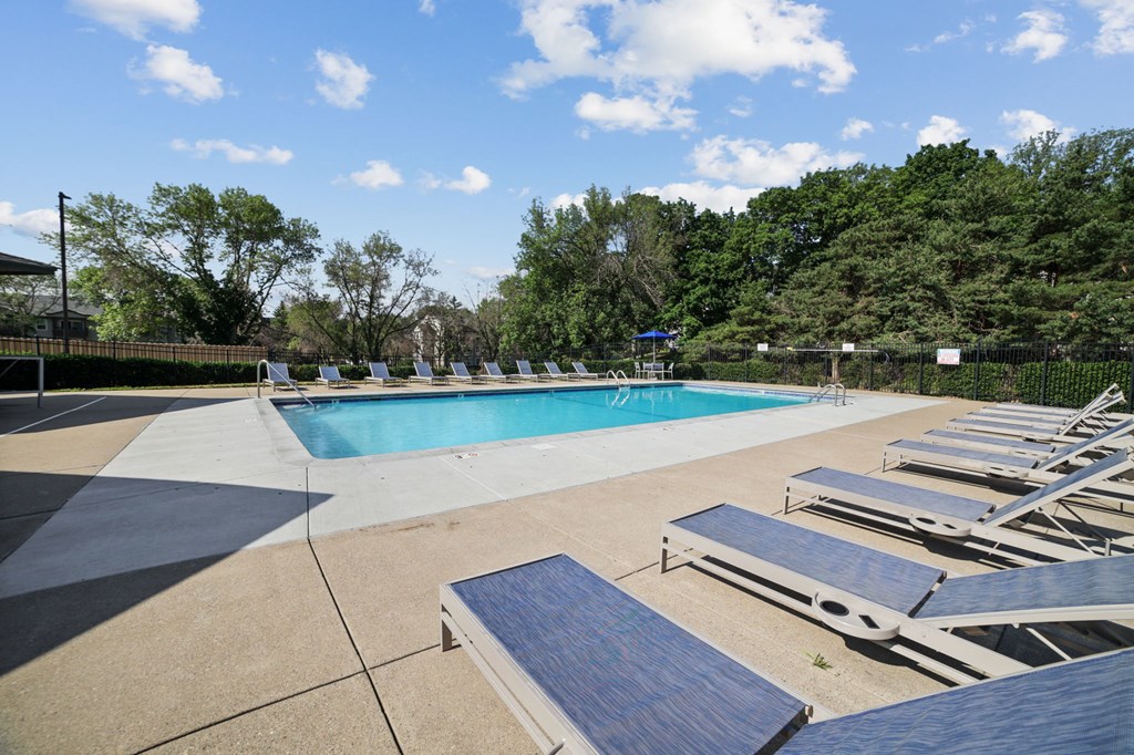 a pool with lounge chairs and trees in the background