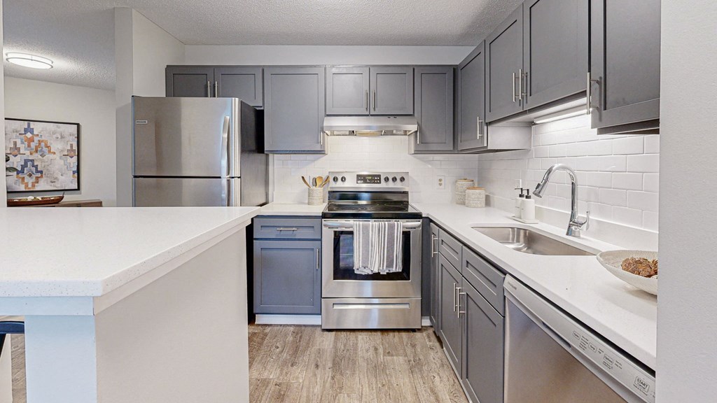 an updated kitchen with stainless steel appliances and white countertops