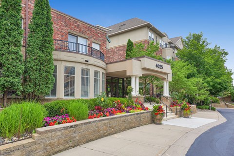 the front of a house with flowers on the sidewalk