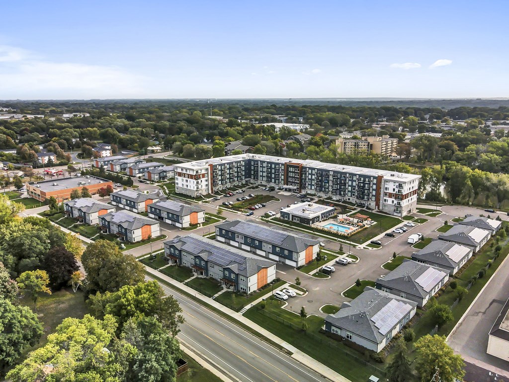an aerial view of a large city with green trees and a highway in the foreground