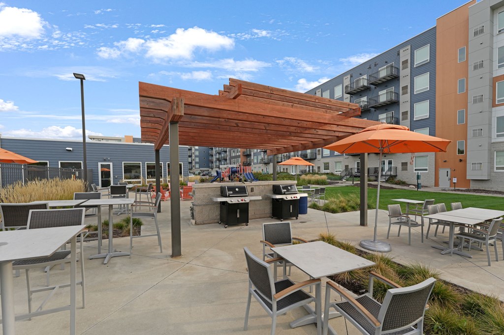 an outdoor patio with tables and chairs and a grill