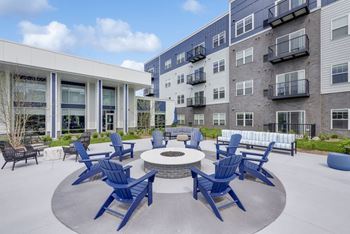 A patio with blue chairs and a fire pit at Lochner Apartments, White Bear Lake, Minnesota