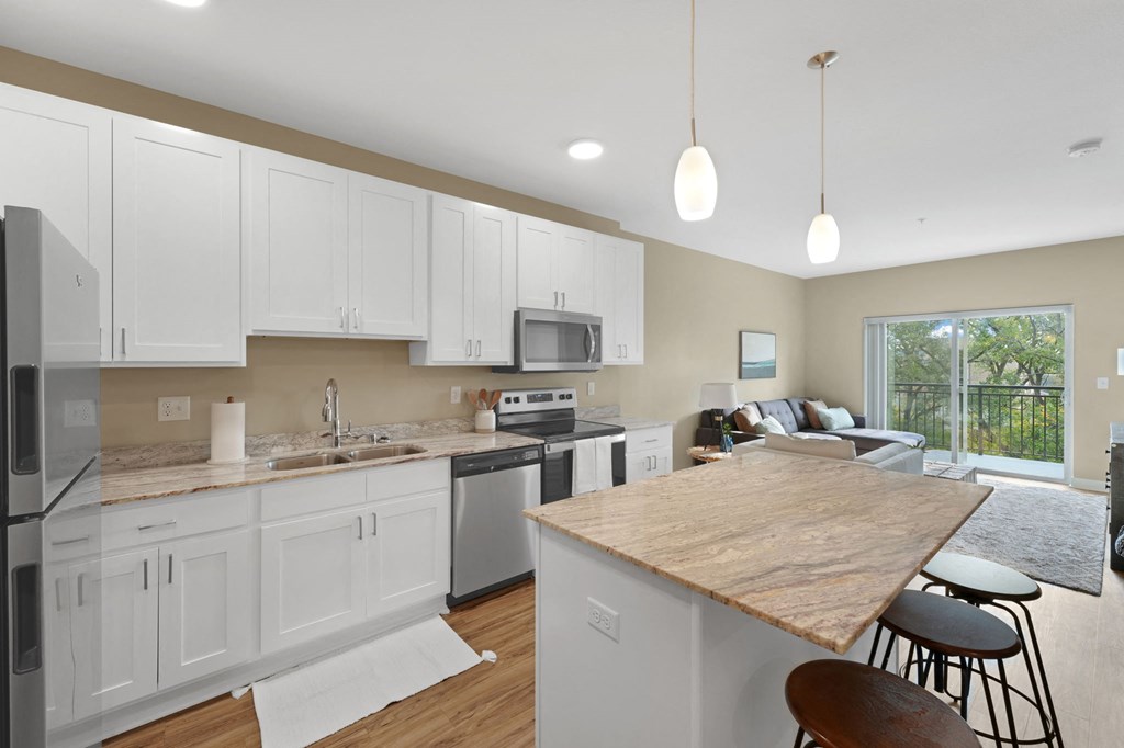 a kitchen and living room with white cabinets and a wooden counter top