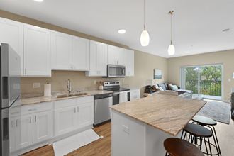 a kitchen and living room with white cabinets and a wooden counter top