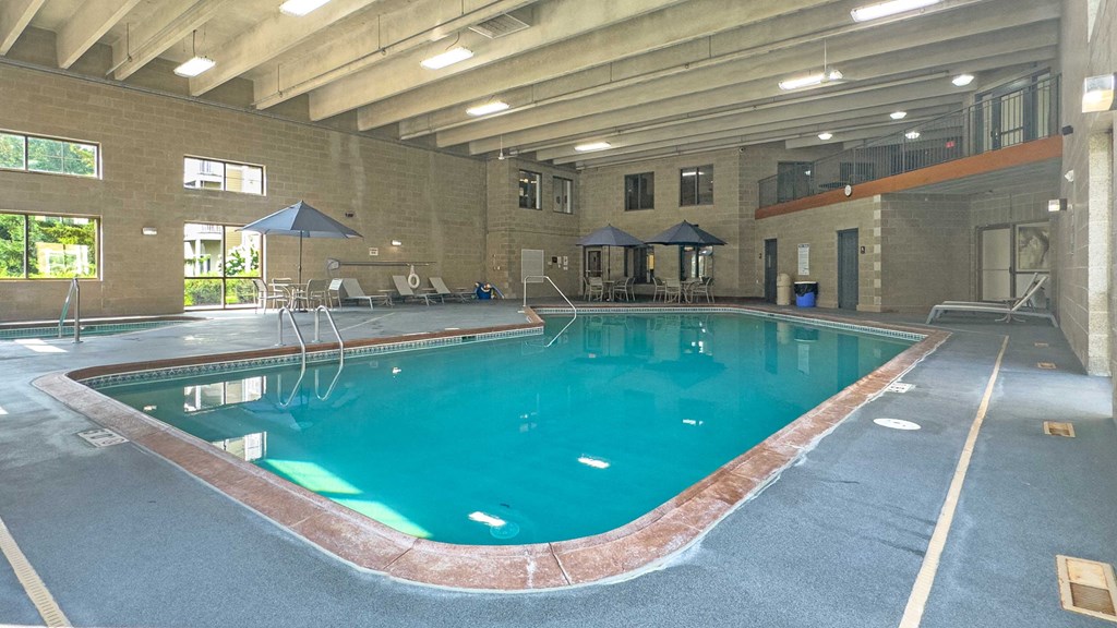 an indoor pool with tables and umbrellas