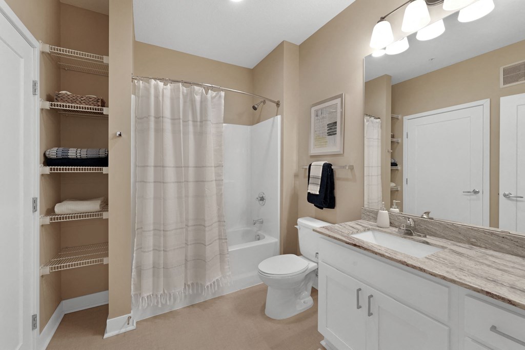 a bathroom with beige walls and a white sink and toilet next to a white shower curtain