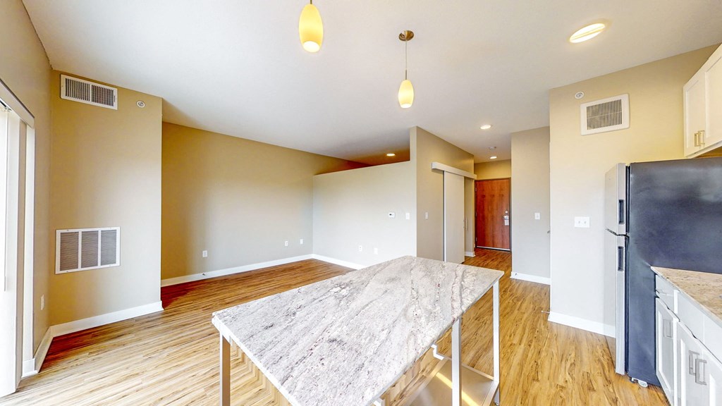a dining room with a marble table and a kitchen with a refrigerator