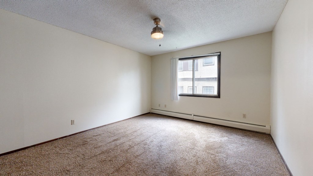 a bedroom with a large window and beige carpet