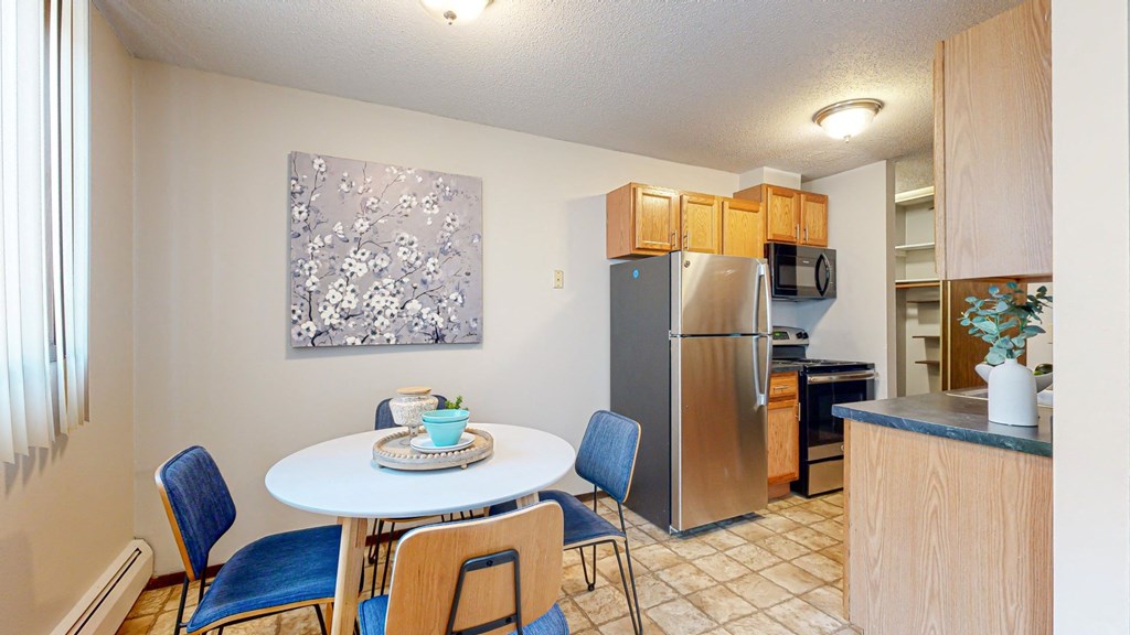 a dining area with a table and chairs and a kitchen in the background