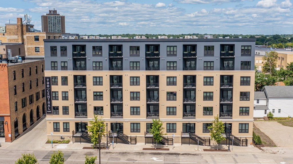 a large apartment building with a blue roof and tan facade