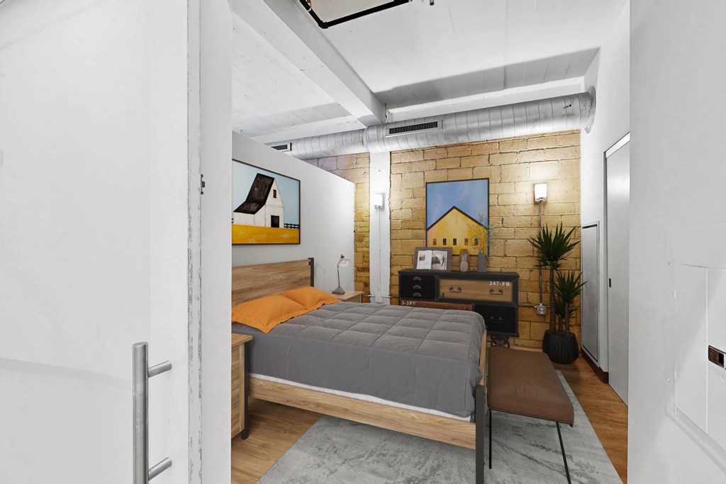 A bedroom with a bed, a chair, and a plant.