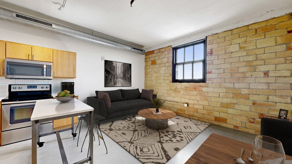 A kitchen with a brick wall and a table with a bowl of fruit on it.