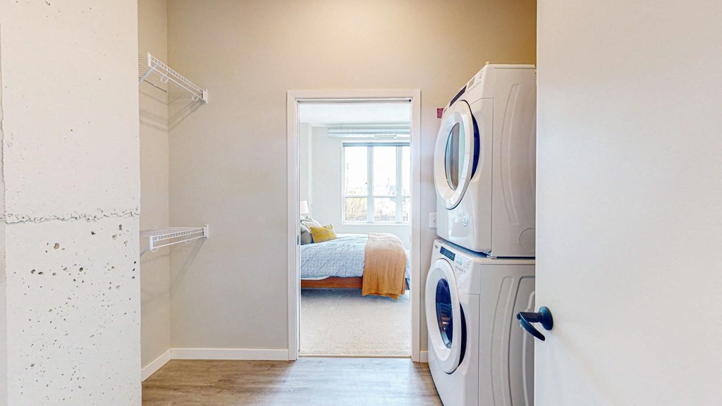 a bedroom with a large window and a washer and dryer