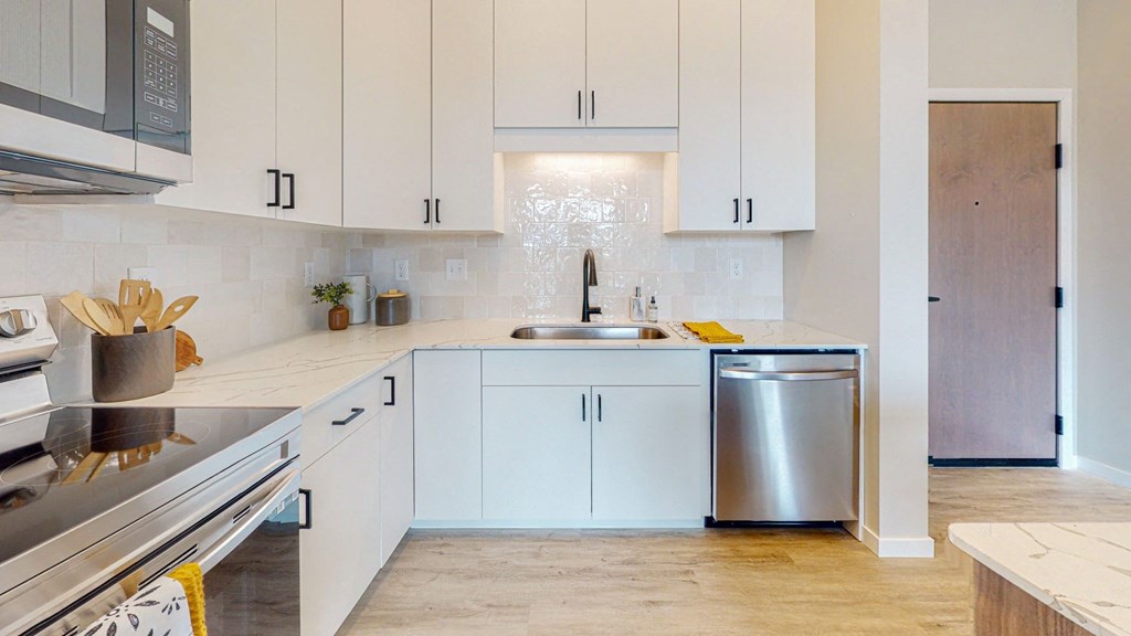 a kitchen with white cabinets and a stainless steel dishwasher