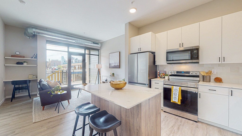 a kitchen with white cabinets and a large island with a marble countertop
