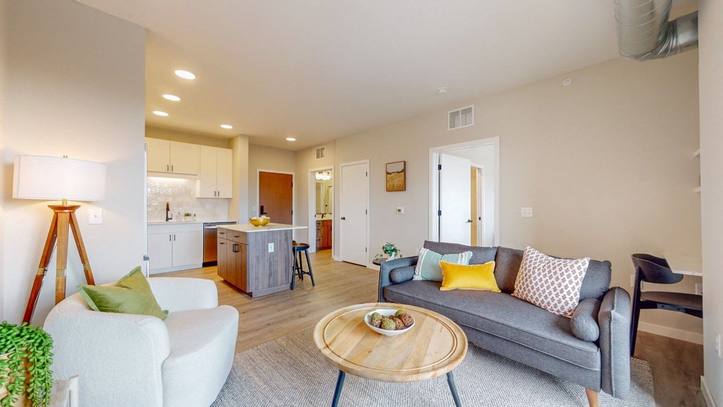 a living room with a couch coffee table and a kitchen in the background