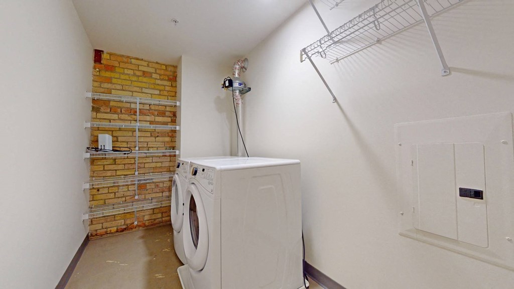 a washer and dryer in a laundry room with a brick wall
