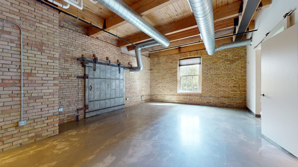 a large empty room with brick walls and a large window