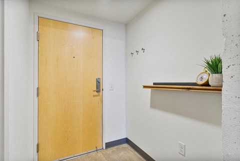 a wooden door in a white room with a wall and a shelf