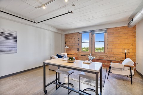a dining room with a table and chairs and a brick wall