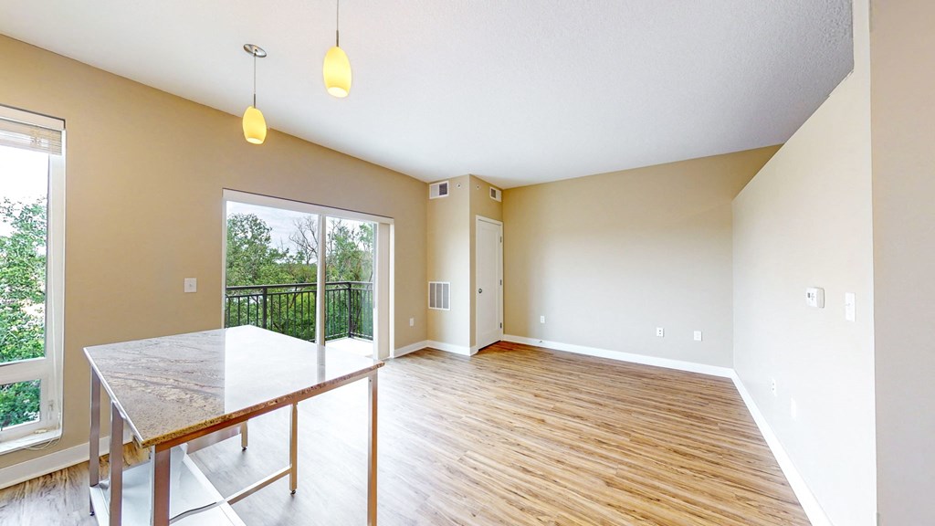 an empty living room with a glass sliding door to a balcony