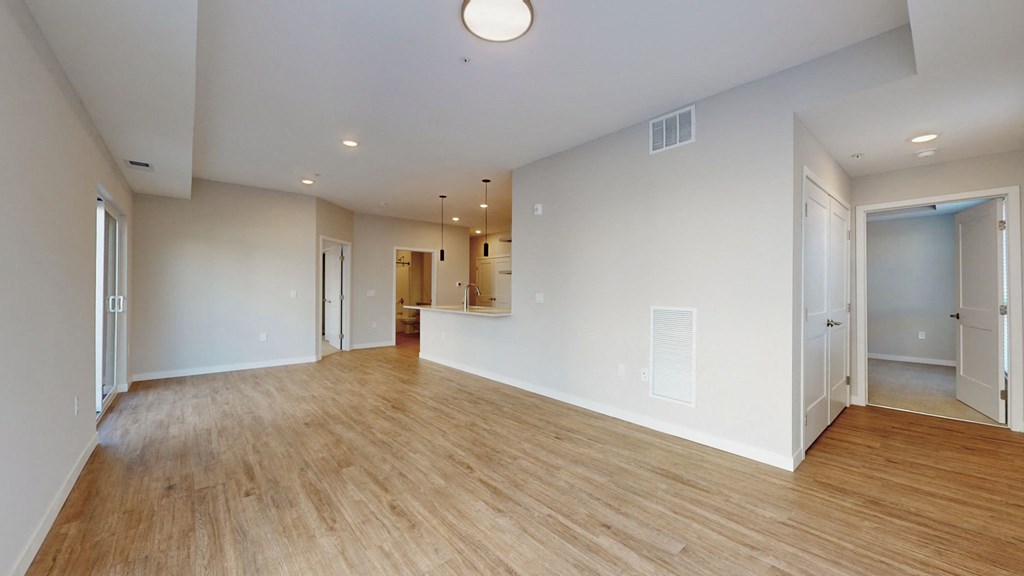 the living room and dining room of an empty house with wood flooring