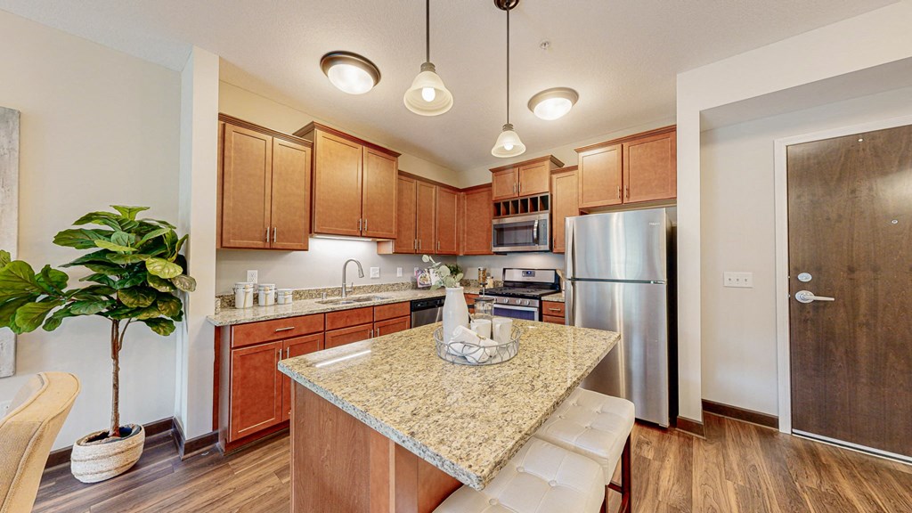a kitchen with a granite counter top and a stainless steel refrigerator