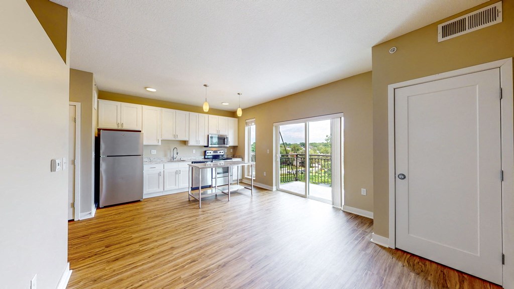 an open living room and kitchen with a door to a balcony