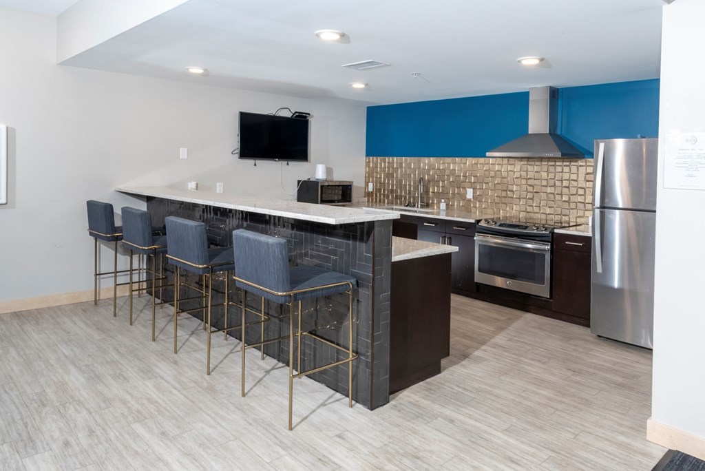 A modern kitchen with a bar area and stainless steel appliances.