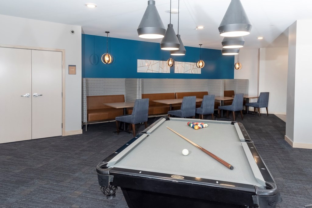 A pool table is in the middle of a room with a blue wall and a white door.