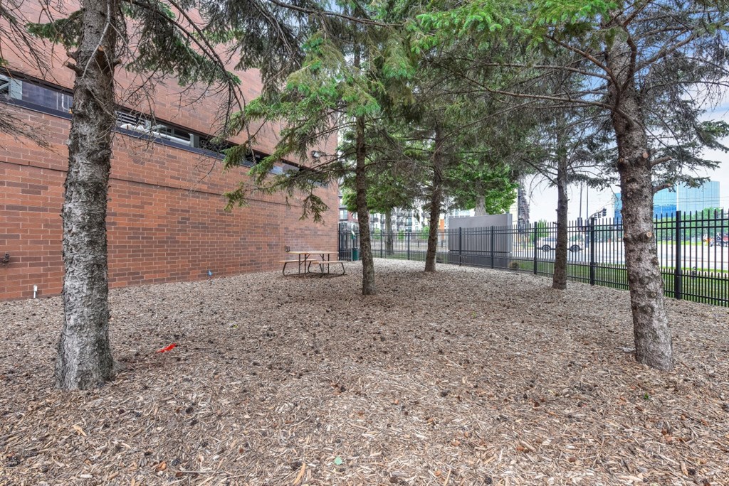 a park with trees and a bench in front of a brick building