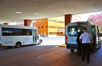 Two Aire Craft buses are parked in a covered area. at Ardor on the Bluffs South Loop Residences Apartments, Bloomington, 55425