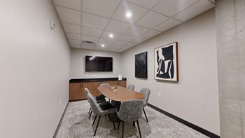 A conference room with a table, chairs, and two framed pictures on the wall at Ardor on the Bluffs South Loop Residences Apartments, Bloomington, MN, 55425