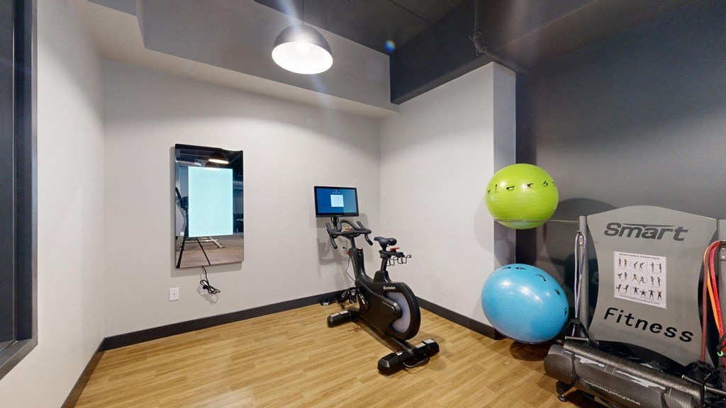 A room with a wooden floor and a wall-mounted TV.