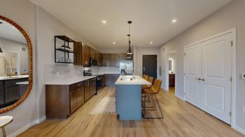 A modern kitchen with wooden floors and a large island at Ardor on the Bluffs South Loop Residences Apartments, Bloomington, MN, 55425