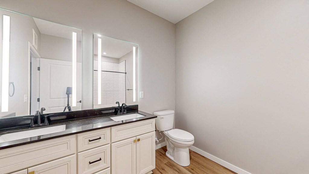 a bathroom with a toilet and a sink and a mirror at Ardor on the Bluffs South Loop Residences Apartments, Bloomington, 55425