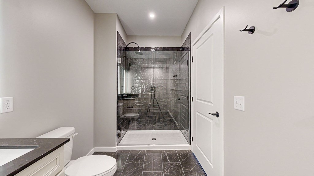a bathroom with a shower and a toilet and a sink at Ardor on the Bluffs South Loop Residences Apartments, Bloomington