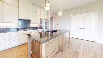 A kitchen with a wooden island and white cabinets at Ardor on the Bluffs South Loop Residences Apartments, Minnesota