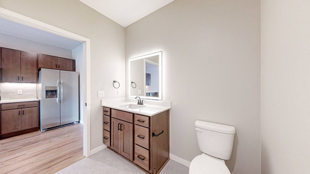 a bathroom with a toilet and a sink and a mirror at Ardor on the Bluffs South Loop Residences Apartments, Bloomington, 55425