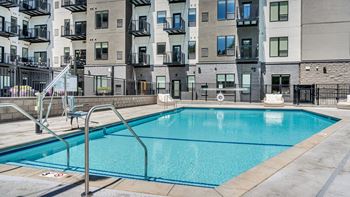A swimming pool in front of a building with a metal railing.